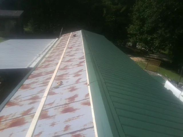 Old rusted panels beside newly installed green metal roofing — Wind Damage Roof Repair by Roofing Brothers in Ridgeway