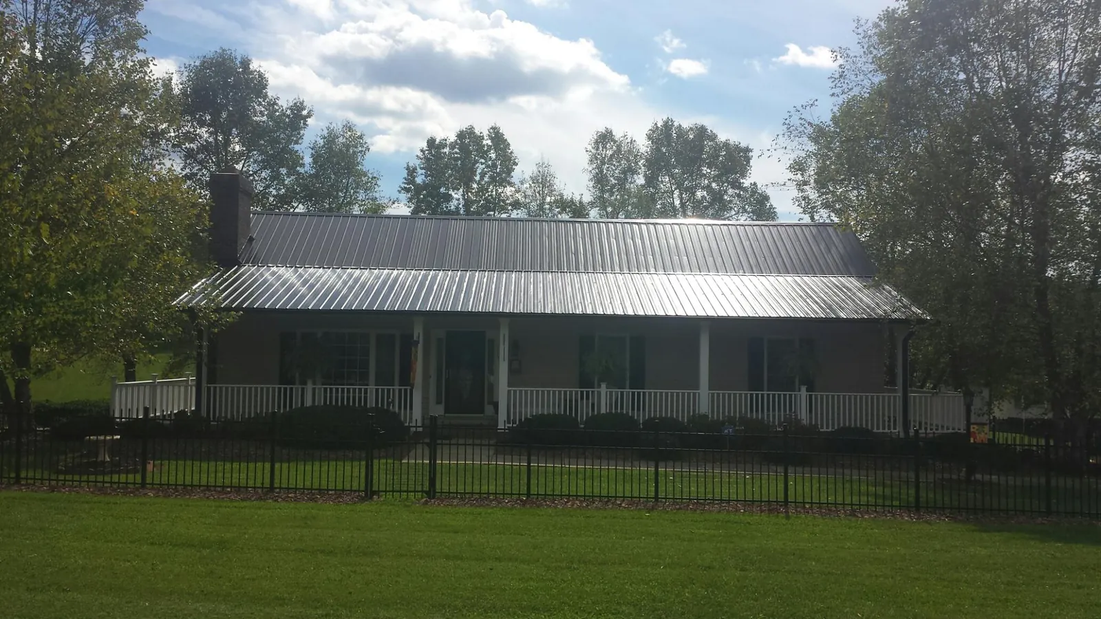 Gray metal roof on a brick ranch with a full width front porch in Ridgeway