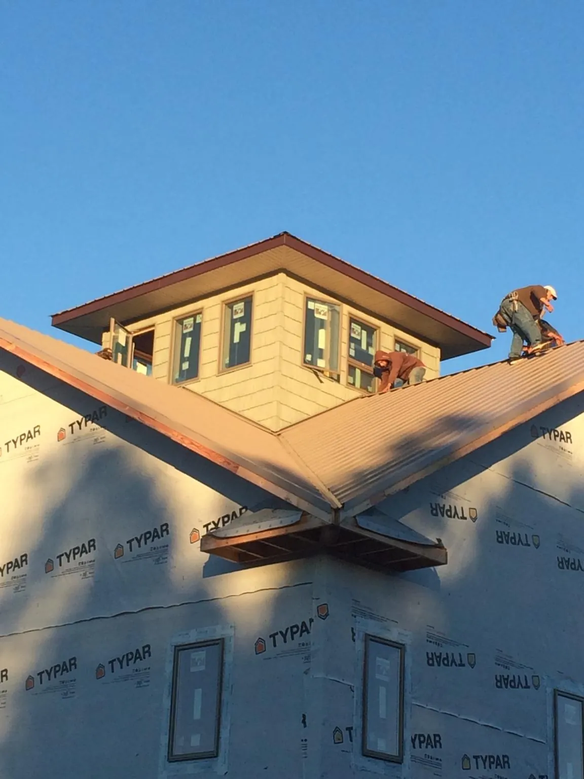 Roofers working around a rooftop cupola on a new metal roof at sunset — Roof Waterproofing in Ridgeway by Roofing Brothers